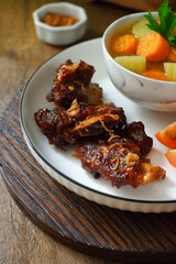 a plate of grilled beef ribs served with vegetables 