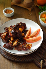 a plate of grilled beef ribs served with vegetables 