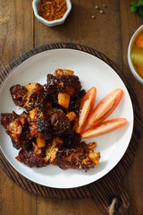 a plate of grilled beef ribs served with vegetables 