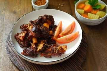 a plate of grilled beef ribs served with vegetables 