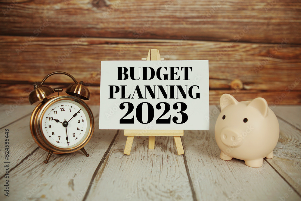 Poster budget planning 2023 text message with alarm clock and piggy saving on wooden background