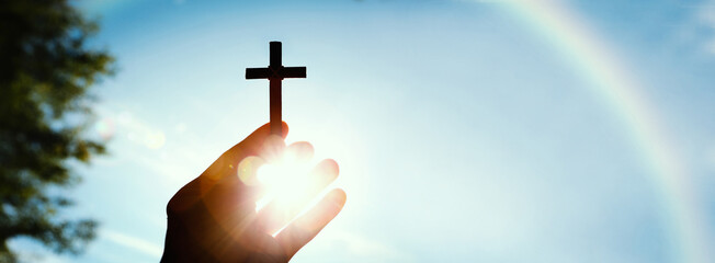 The background of the sun shining through the fingers and the blue sky and the holy cross...