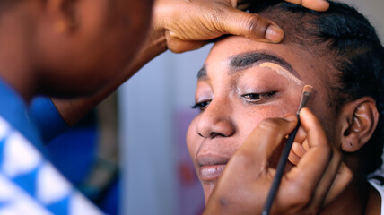 Make up artist drawing over the eyebrow of a model during make up