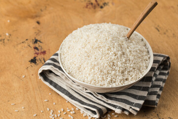  Raw round white rice in a bowl close-up on a wooden background. Healthy food.