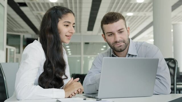 Young positive woman sales agent shows product on laptop to man client tells about profitable offer girl recruit office worker tells mentor development of new progressing strategy planning workflow