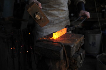 Almaty, Kazakhstan - 09.24.2015 : A blacksmith makes a metal holder for knives and tools in the workshop.