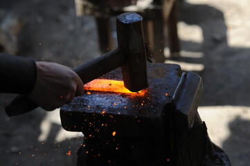 Almaty, Kazakhstan - 09.24.2015 : A blacksmith makes a metal holder for knives and tools in the...