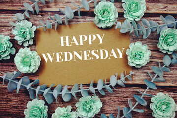 Happy Wednesday typography text on paper card decorate with flower on wooden background