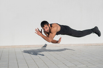 Obraz premium A man in black sportswear jumps while doing push-ups outdoors.