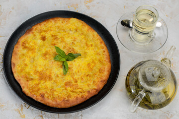 baked Kubdari flatbread in a plate on a white background with tea
