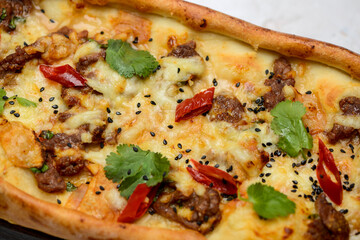 large khachapuri with meat, greens and chili pepper on a plate on a white background, macro photo
