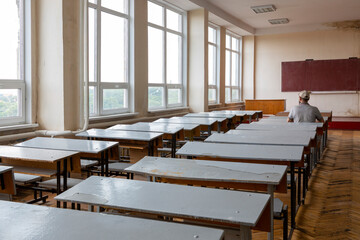 Detail Interior classroom with blackboard on the wall and a person at the desk