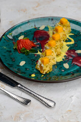 dessert pancakes wrapped in a roll with mango in a plate with strawberries vertical photo

