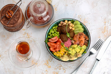 breakfast with salmon falafel and vegetables on a white background with tea
