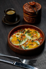fried scrambled eggs in a clay pan vertical photo on a dark background
