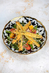 fried quinoli in a plate with tomatoes and greens vertical photo
