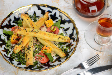 fried quinoli in a plate with tomatoes and greens on the table with tea macro photo
