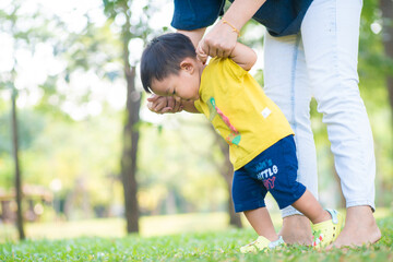 Obraz premium Toddler asian boy practice walking on green grass park with mom