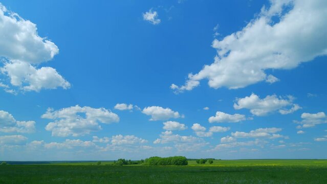 Shadows of flowing clouds in the sky flowing on the green meadow field of countryside. Wide shot. Timelapse.