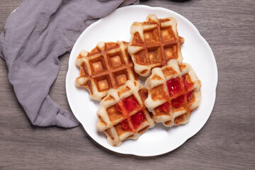 Four waffles in a white plate.and gray background.
