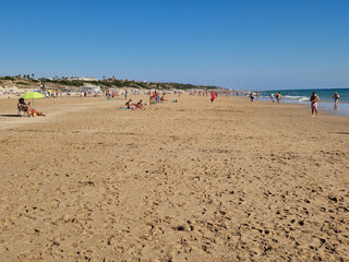 people walking along the seashore, early in the morning, at La Barrosa beach in Sancti Petri, Cadiz, Spain