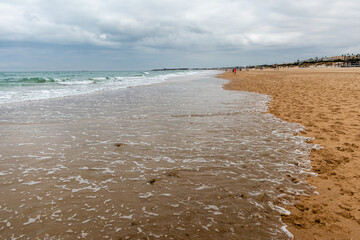 people walking along the seashore, early in the morning, at La Barrosa beach in Sancti Petri, Cadiz, Spain