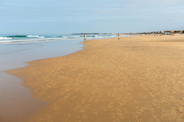 people walking along the seashore, early in the morning, at La Barrosa beach in Sancti Petri, Cadiz, Spain