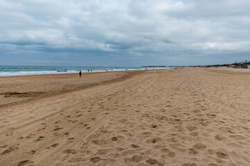 people walking along the seashore, early in the morning, at La Barrosa beach in Sancti Petri, Cadiz, Spain
