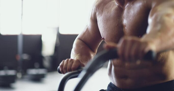 Sexy gym man training on exercise bike with six pack abs, strong body and muscle. Sweat, fitness challenge and workout of bodybuilder cycling on stationary bicycle machine for cardio in health club