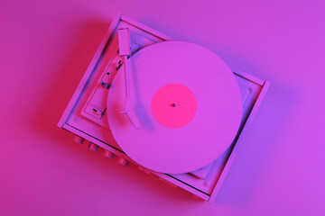 White vinyl record player in pink-blue neon gradient light. Minimalism music concept. Top view