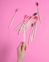 Hand selects Eco-friendly bamboo toothbrush among the set on pink background