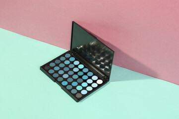 Beauty and fashion minimalistic scene. Eye shadow palette on a blue pink pastel background with trendy shadows. Creative layout