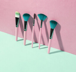 Beauty and fashion minimalistic scene. Makeup brushes on blue pink pastel background with trendy shadows. Creative layout