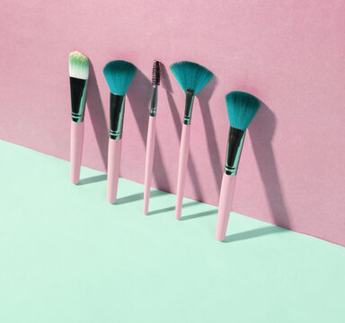 Beauty and fashion minimalistic scene. Makeup brushes on blue pink pastel background with trendy shadows. Creative layout