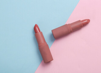 Tubes of pink lipstick on blue pink pastel background