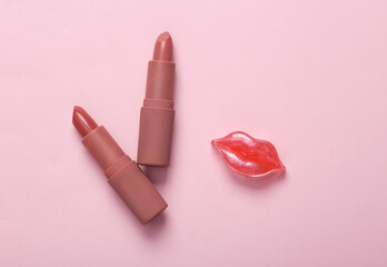 Tubes of pink lipstick and lips on pink pastel background