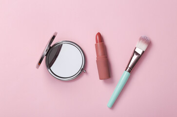 Beauty accessories on a pink background. Lipstick, mirror and make-up brush. Top view