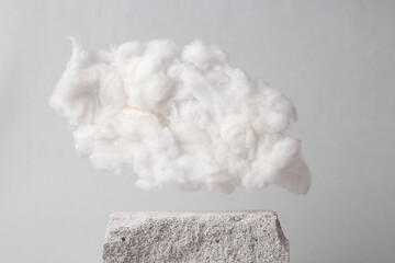 Minimalistic composition with natural porous white stones and cloud on gray background