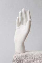 Minimalistic abstract composition of a white plastic hand on a podium stone
