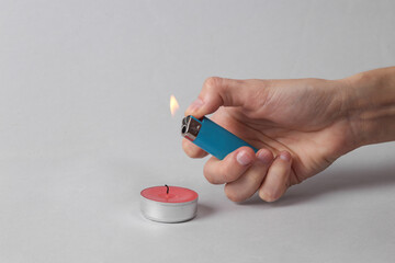 Woman's hand lights aromatic candle on a gray background. aromatherapy