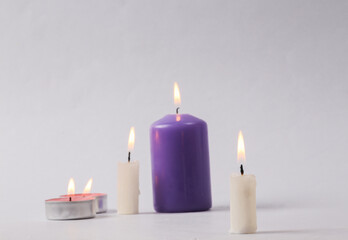 Obraz na płótnie Canvas Different types and sizes Flaming wax candle on a gray background