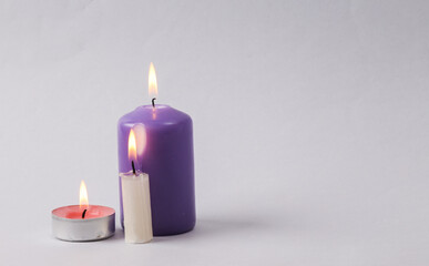 Fototapeta na wymiar Different types and sizes Flaming wax candle on a gray background. Copy space
