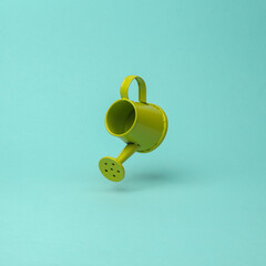 Watering can flying in antigravity on mint green background with shadow. Levitation object in the air. Creative minimal layout