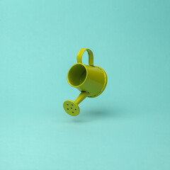 Watering can flying in antigravity on mint green background with shadow. Levitation object in the...