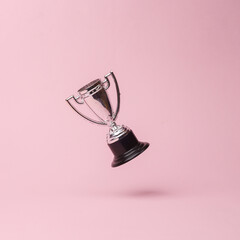 Silver Competition Cup in antigravity on pink background with shadow. Levitation object in the air. Creative minimal layout