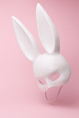 Sexy white rabbit mask with long ears flying in antigravity on pink background with shadow....