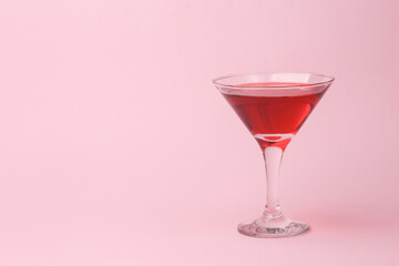 Martini glass with red drink cocktail on pink background