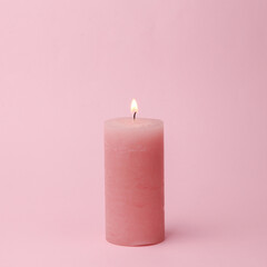 Pink flaming candle on pink background. Pastel color trend