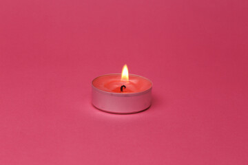 Fototapeta na wymiar Flaming scented tea candle on pink background