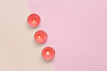 Flaming aroma candles on pink beige background. Top view